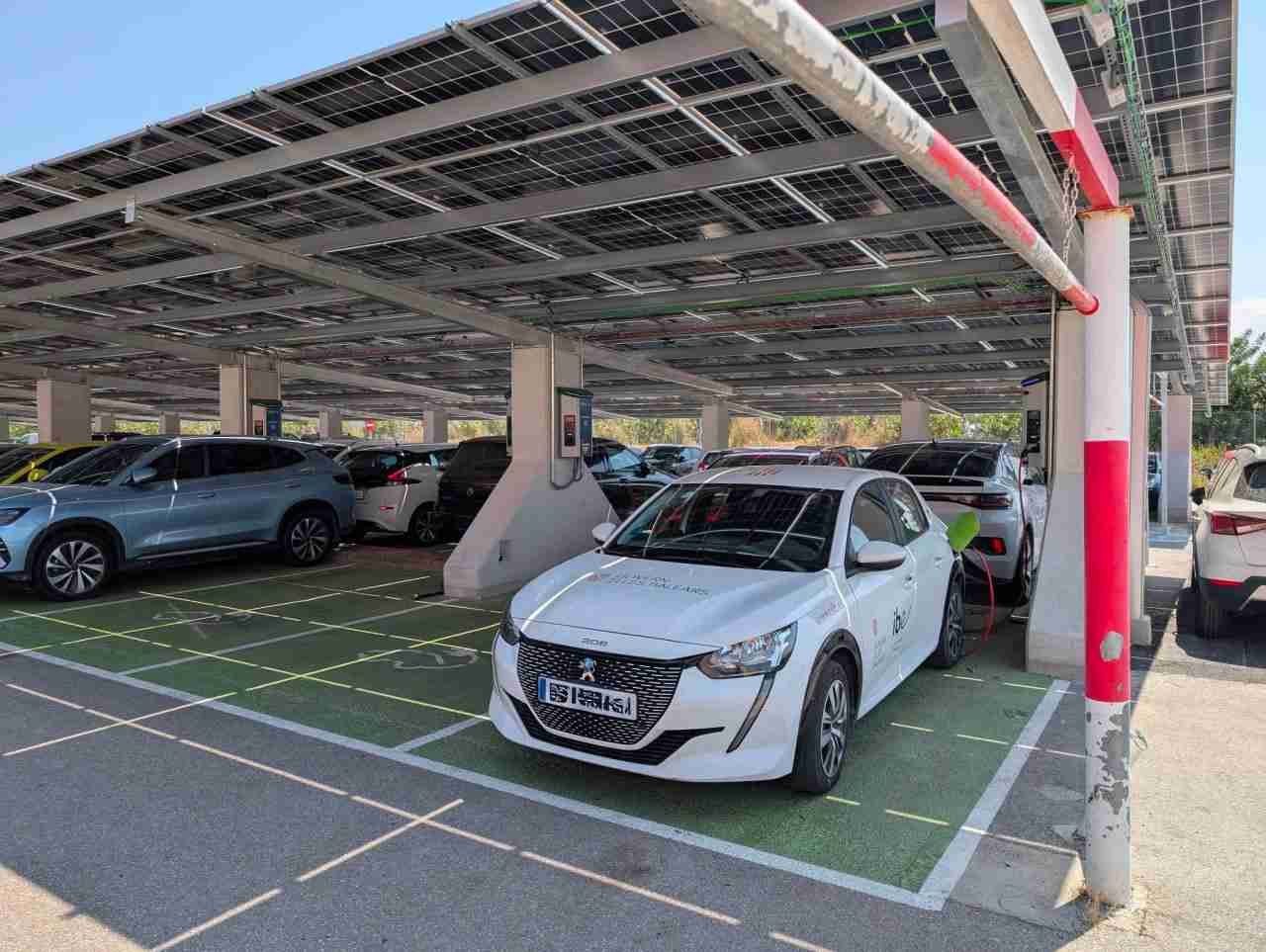 Un coche eléctrico blanco carga en el nuevo aparcamiento solar del Hospital Comarcal de Inca