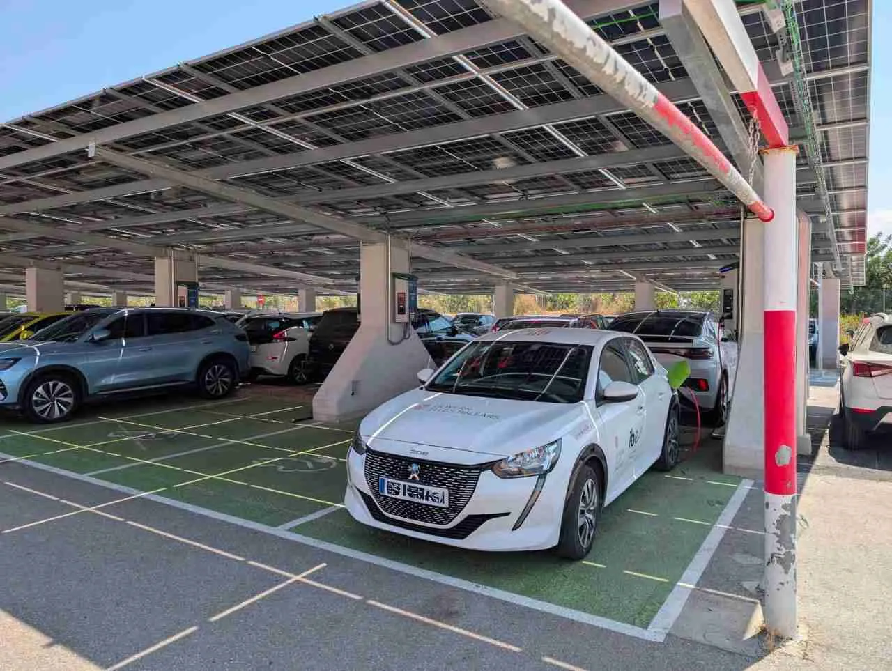 Un coche eléctrico blanco carga en el nuevo aparcamiento solar del Hospital Comarcal de Inca