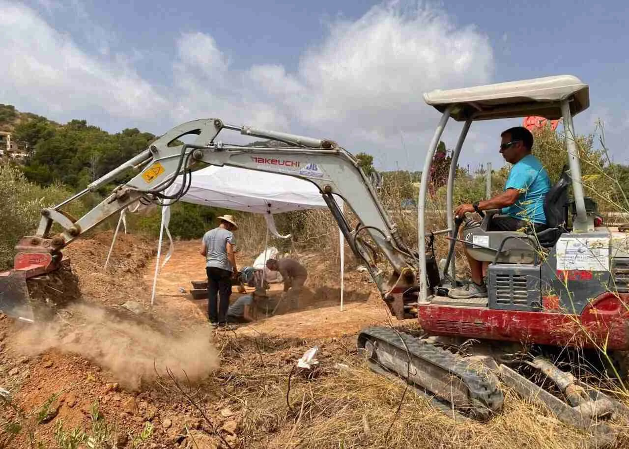 Excavadora y arqueólogos realizando trabajos de campo del V Plan de Fosas en Son Servera