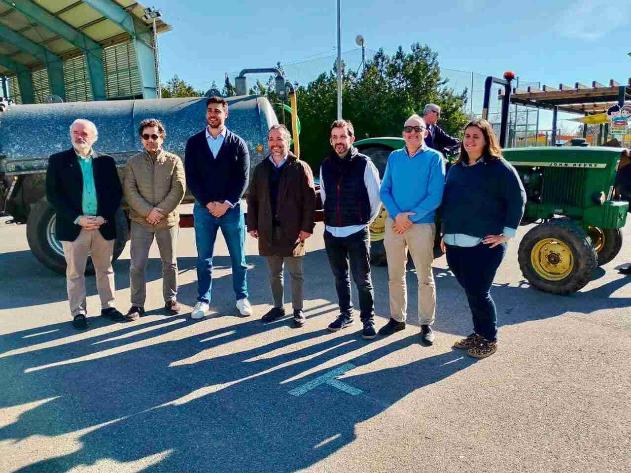 Representantes institucionales posando en exteriores junto a un tractor agrícola