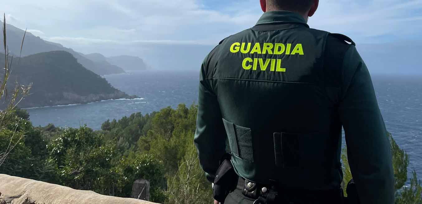 Agente de la Guardia Civil de espaldas observando la costa y la montaña en Mallorca