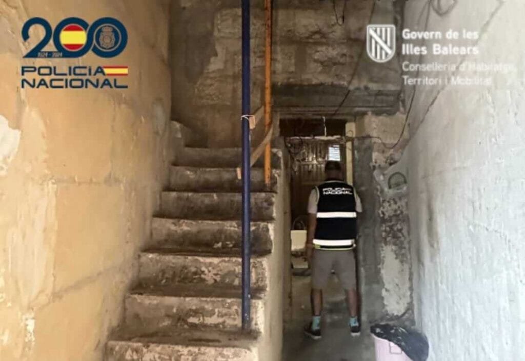Agente de la Policía Nacional en la escalera apuntalada durante la inspección en la casa patera en Vía Majòrica