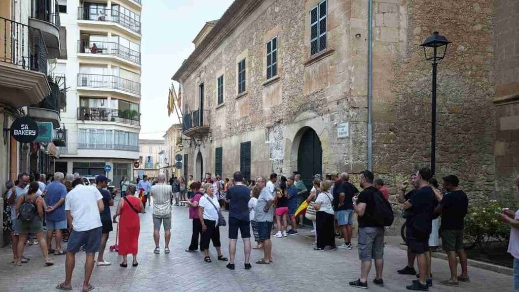 Grupo de personas concentradas en la calle del Ayuntamiento de Manacor con banderas de España
