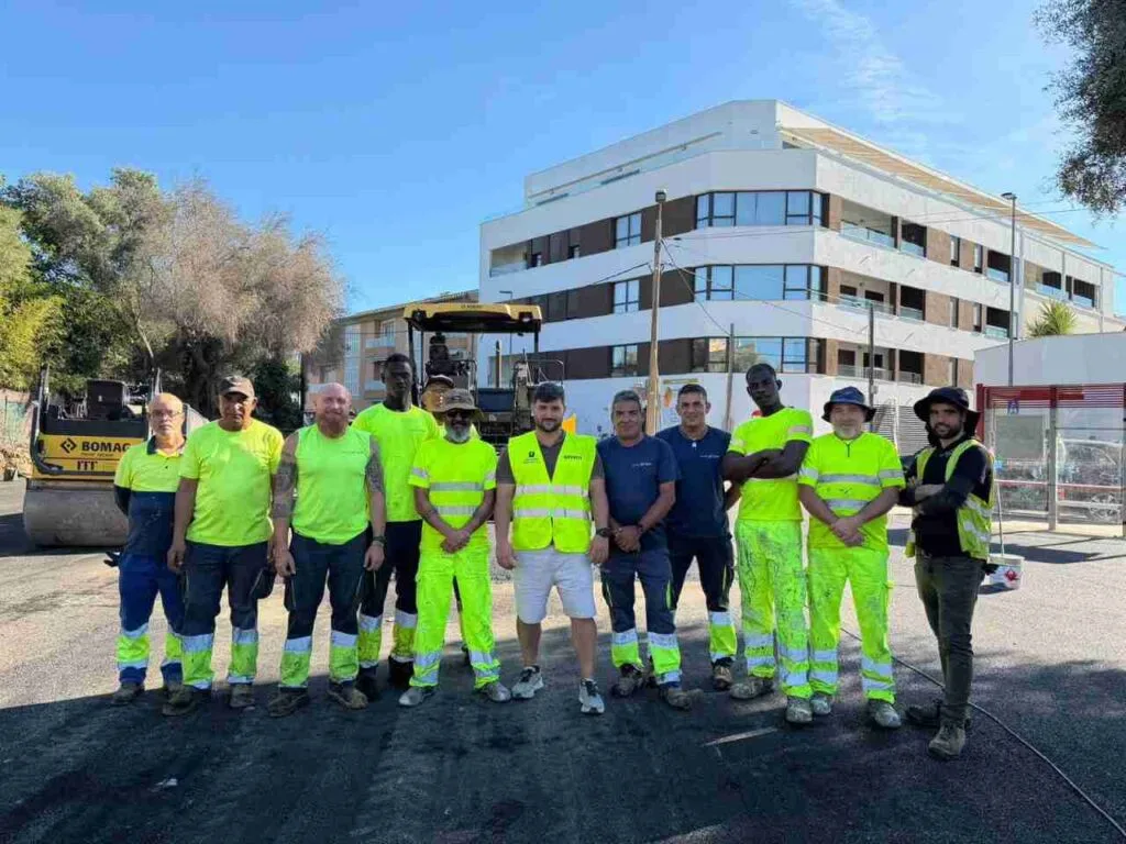 El regidor de Movilidad Bernat Grimalt con chaleco reflectante junto a la cuadrilla de trabajadores y maquinaria de asfaltado