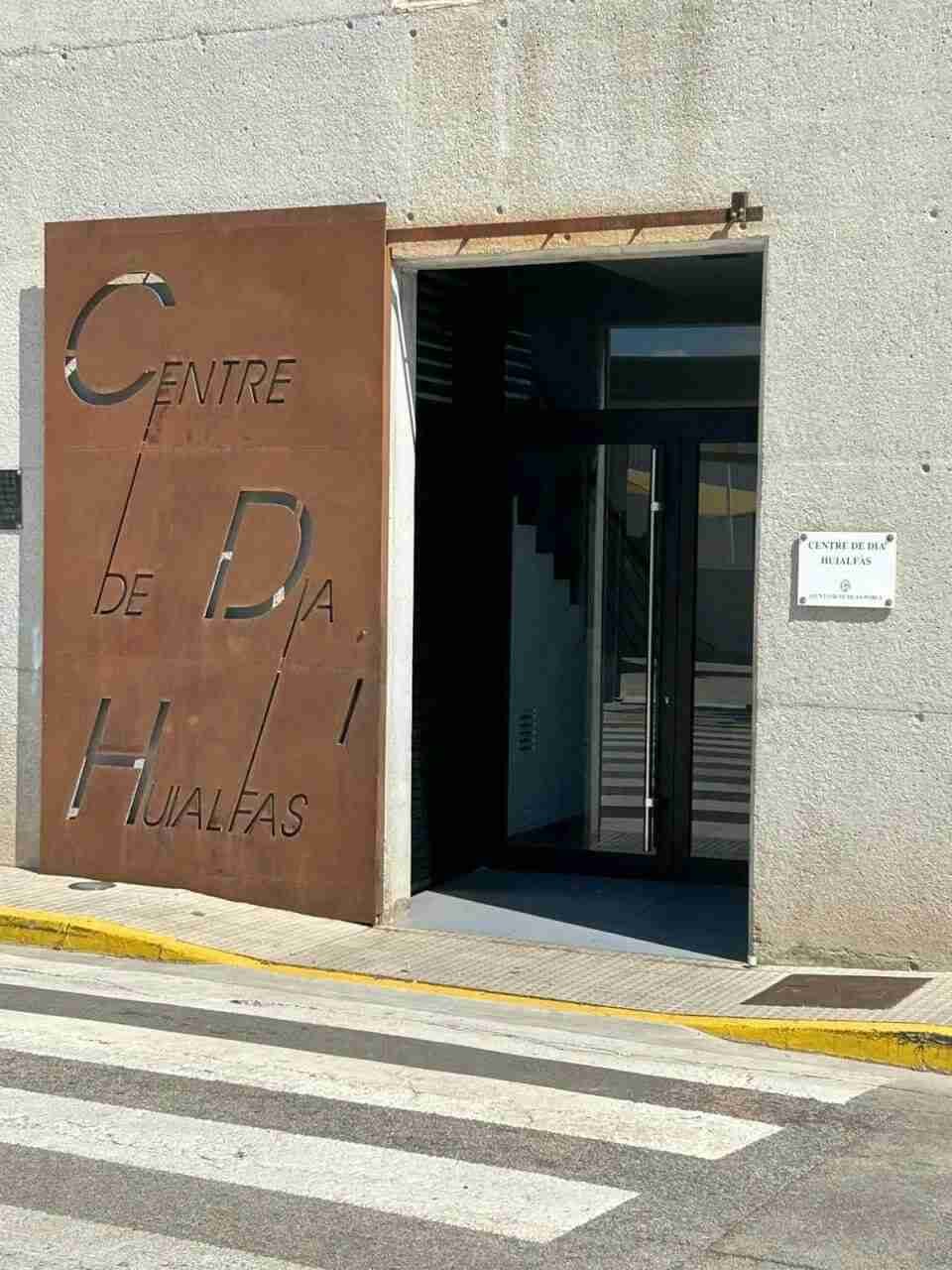 Fachada con puerta metálica y placa identificativa del Centro de Día Huialfàs de Sa Pobla