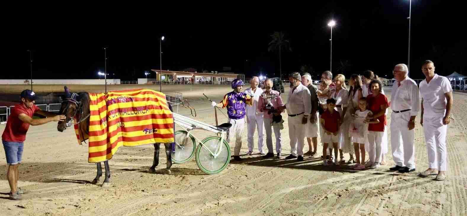Ganadores y autoridades posan junto al caballo cubierto con la bandera balear en la pista