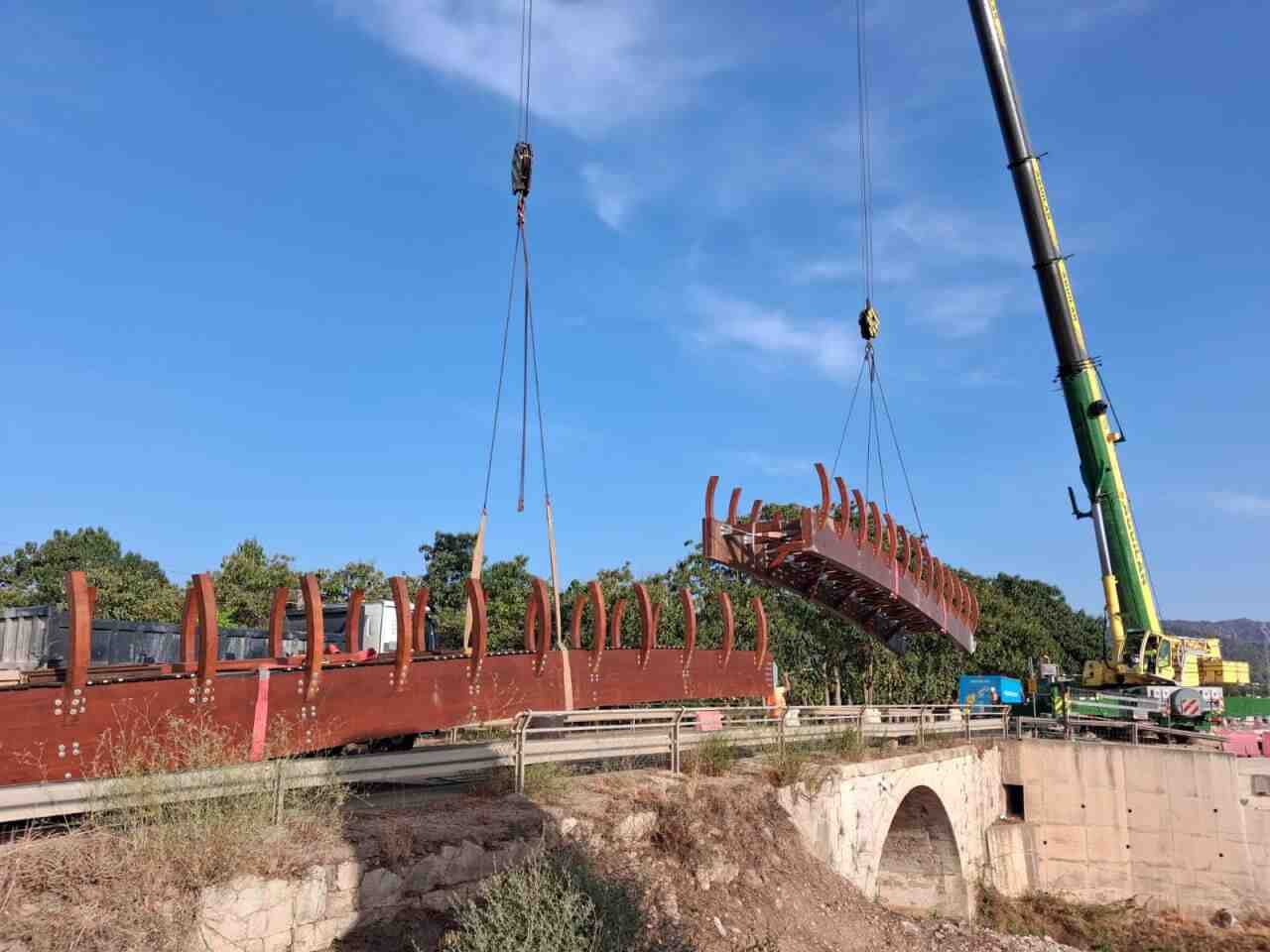 Grúas instalan la estructura de madera de la pasarela sobre el torrente de Sant Miquel en Crestatx