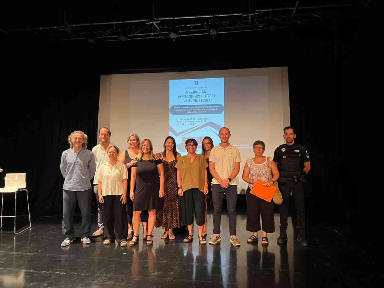 Participantes y ponentes posan en el escenario del Teatre La Unió durante la jornada de absentismo escolar