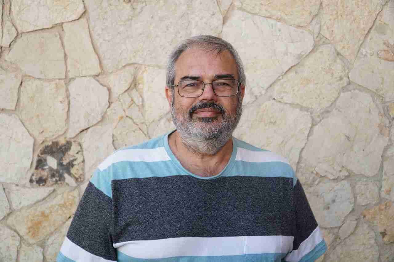 José Manuel García Mena, portavoz del PSOE de Sineu, posa con gafas y camiseta de rayas frente a una pared de piedra