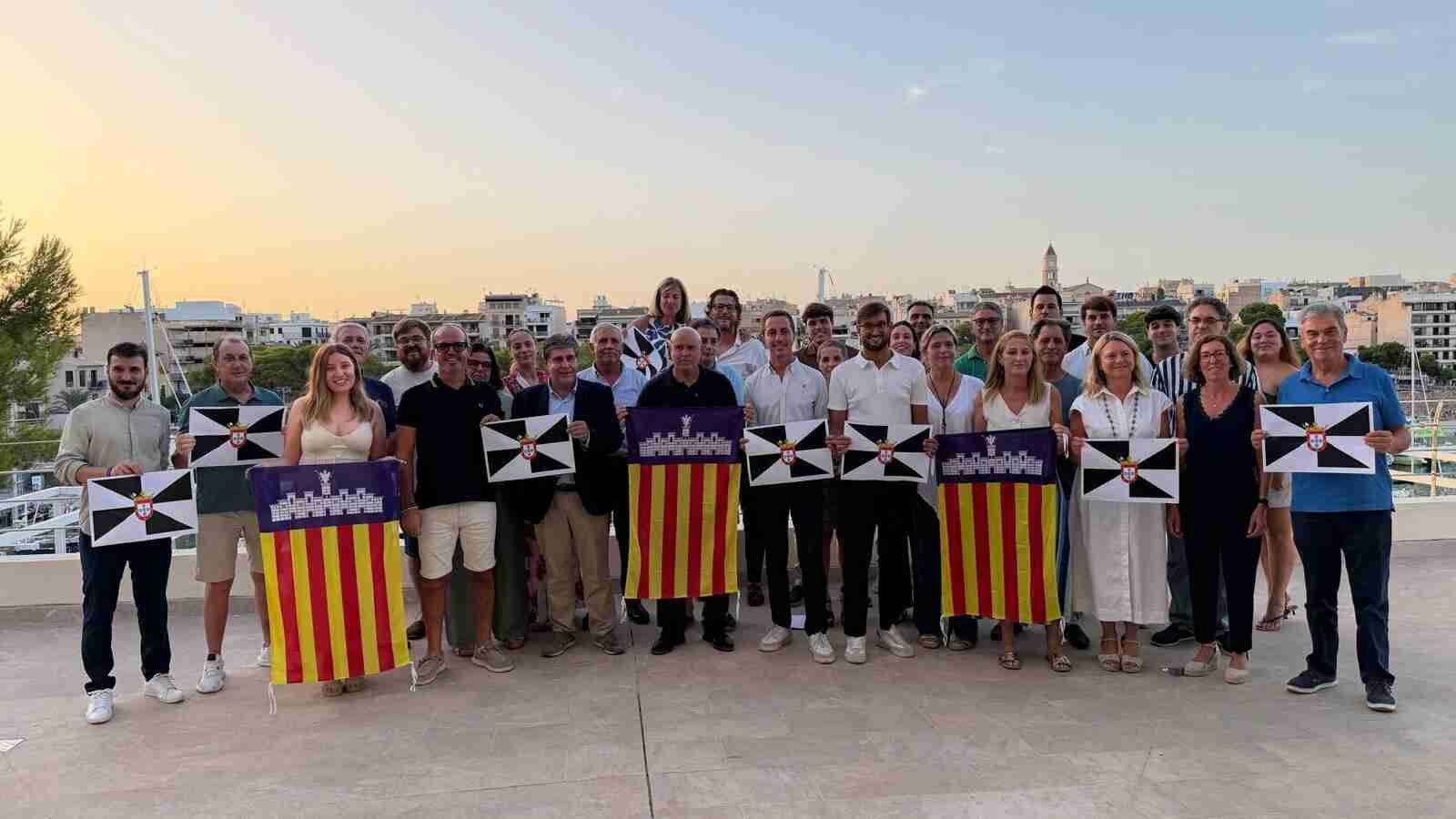 Cargos de la Junta Local del PP de Manacor posando en una terraza con enseñas de Baleares y Ceuta