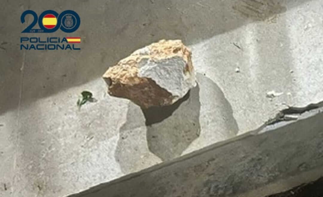 Piedra irregular sobre una superficie de hormigón junto al logotipo de la Policía Nacional