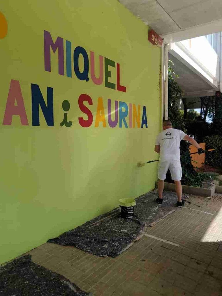 Operario pintando con rodillo una pared exterior del colegio Miquel Duran i Saurina en Inca