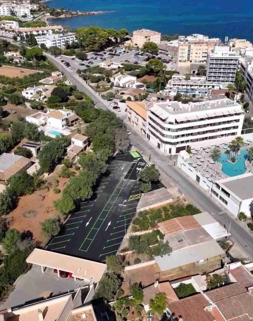 Vista aérea del nuevo aparcamiento asfaltado con flechas direccionales y señal de STOP pintadas en el suelo en Cala Millor