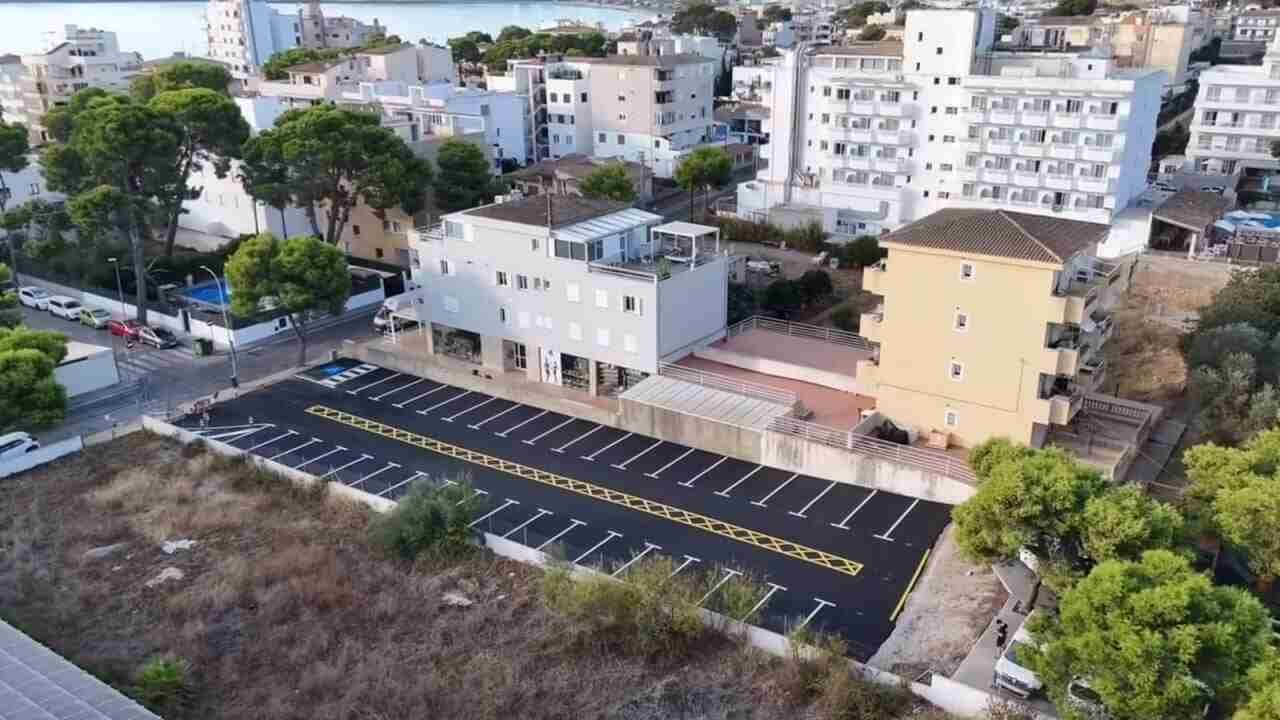 Vista aérea de un aparcamiento recién asfaltado y señalizado con líneas blancas y amarillas en Cala Millor