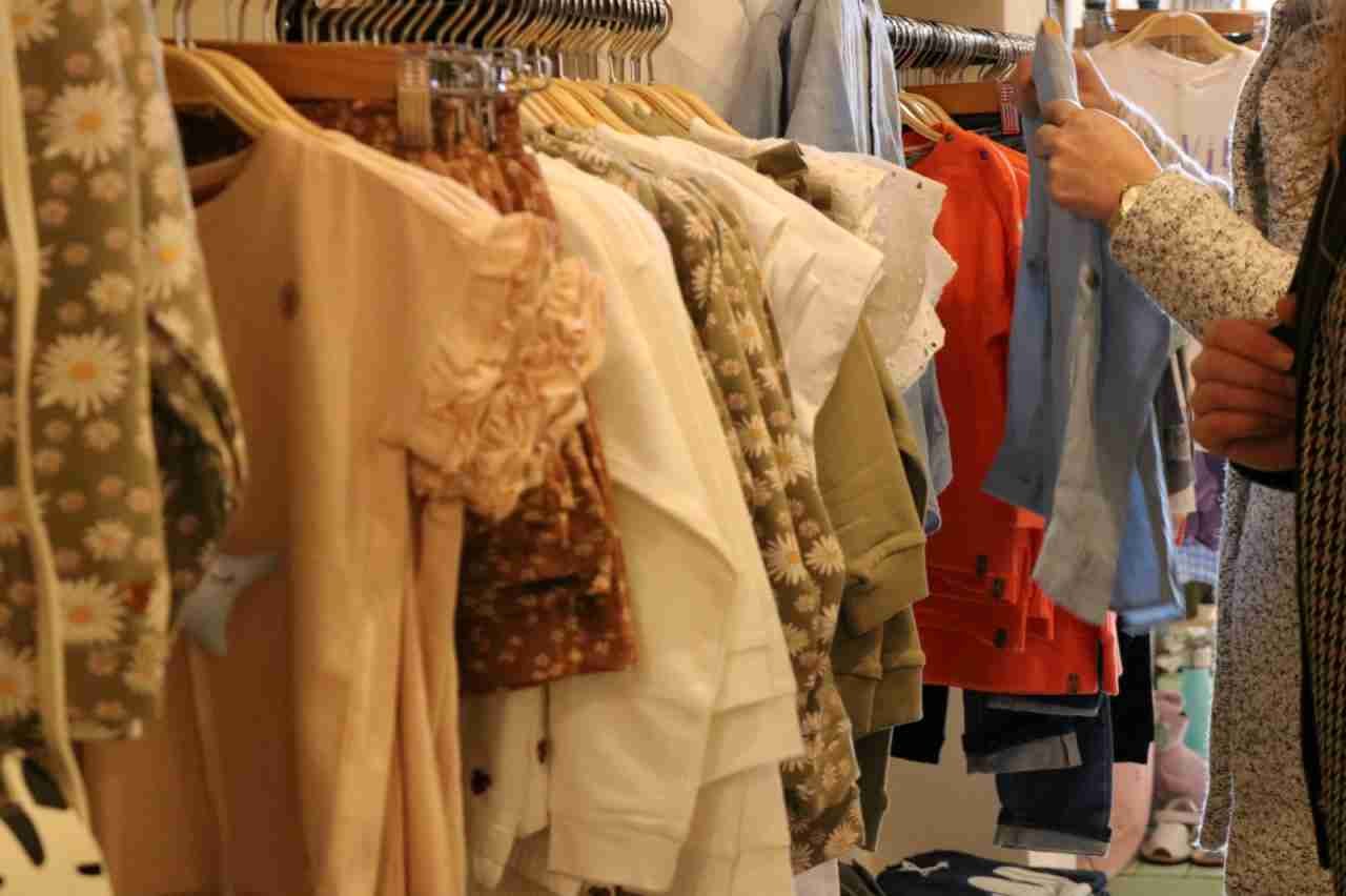 Cliente examinando prendas infantiles en perchas dentro de un comercio textil en la campaña de bonos de Felanitx