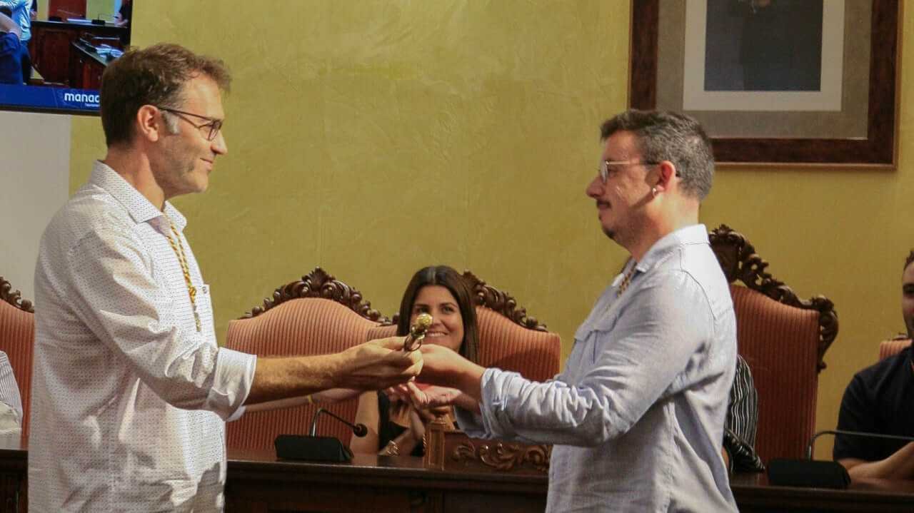 Miquel Oliver entregando la vara de mando de alcalde a Ferran Montero en el salón de plenos de Manacor