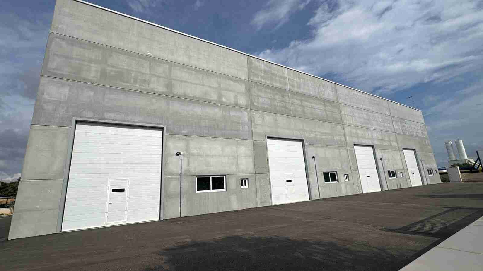 Fachada exterior de hormigón con puertas de acceso de las cuatro naves industriales en Felanitx