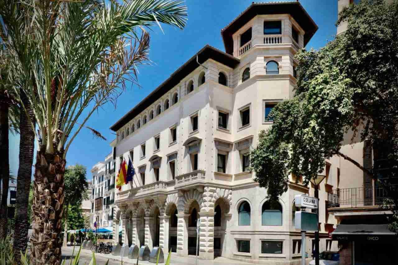 Fachada del edificio de la Delegación del Gobierno en Palma de Mallorca con banderas oficiales y soportales